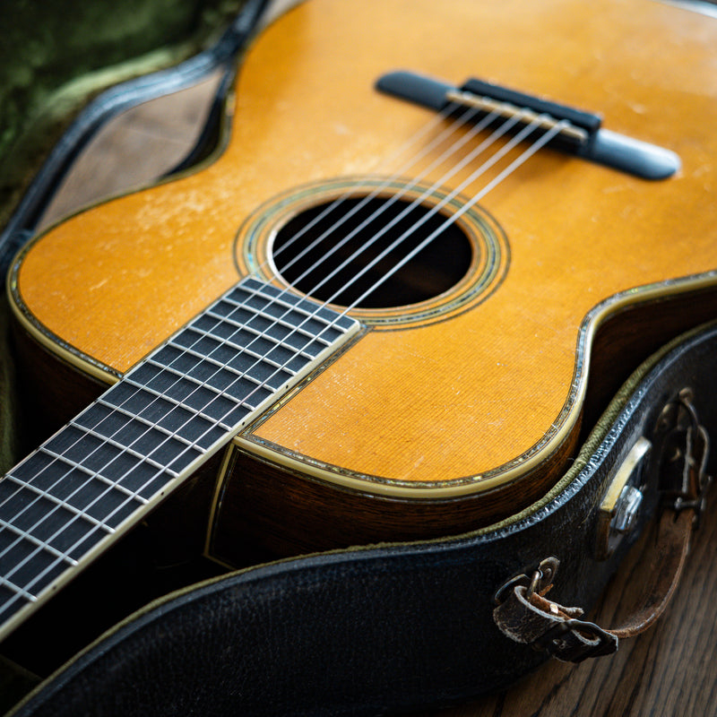 Photo of vintage Martin guitar in case on wooden floor