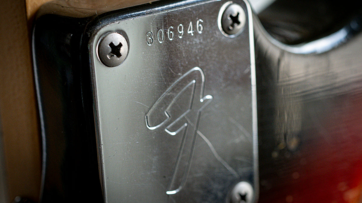 Close-up of vintage Fender guitar neck plate showing serial number