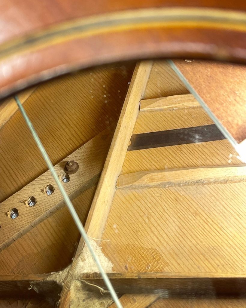 Showing a loose brace under the bridge on a 30's Gibson guitar